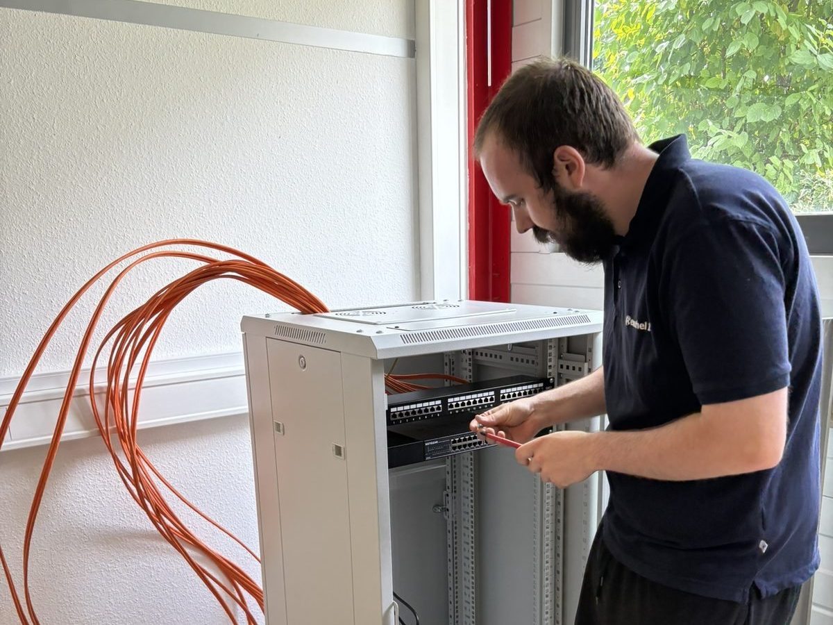 Ein Techniker von Reuschel IT baut ein Patchfeld in einen Netzwerkschrank ein